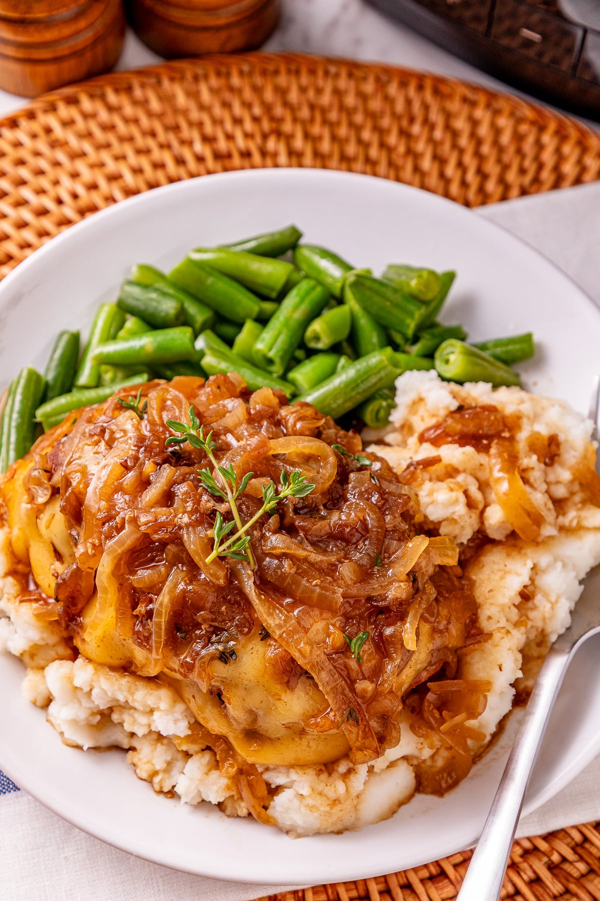 French onion chicken on a plate with mashed potatoes and green beans.
