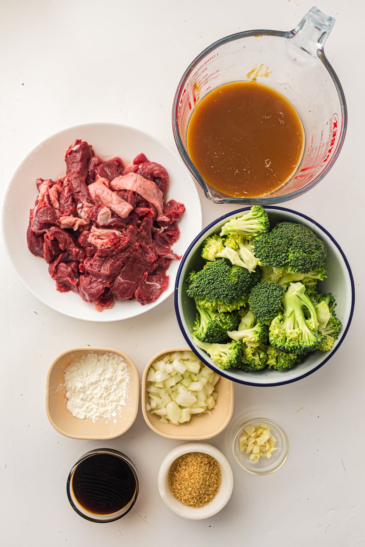 Ingredients for beef and broccoli in the slow cooker in small bowls on kichen counter.
