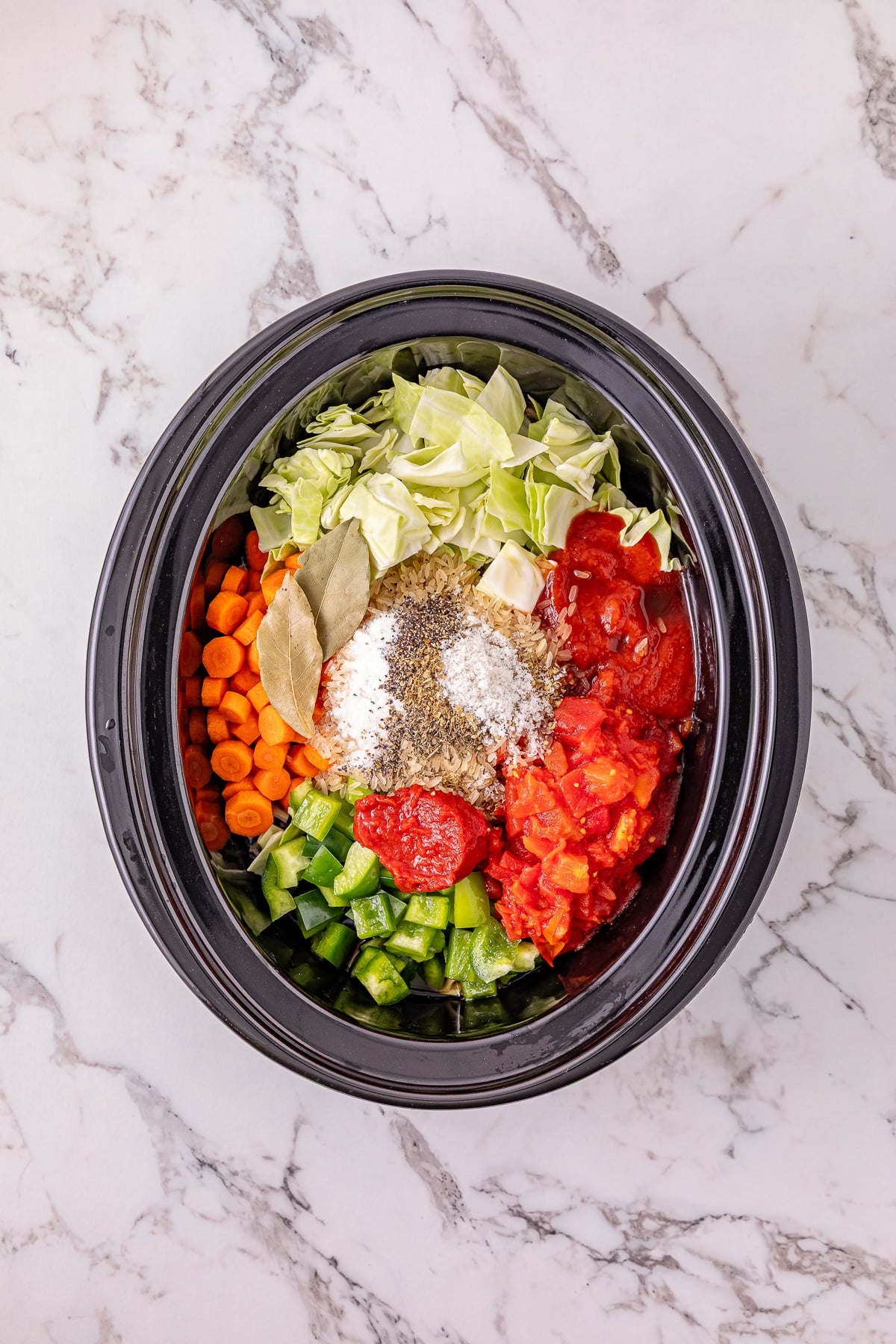 Carrots, bell pepper, uncooked rice, cabbage, diced tomatoes, tomato sauce, tomato paste, and Worcestershire sauce are added to the slow cooker.