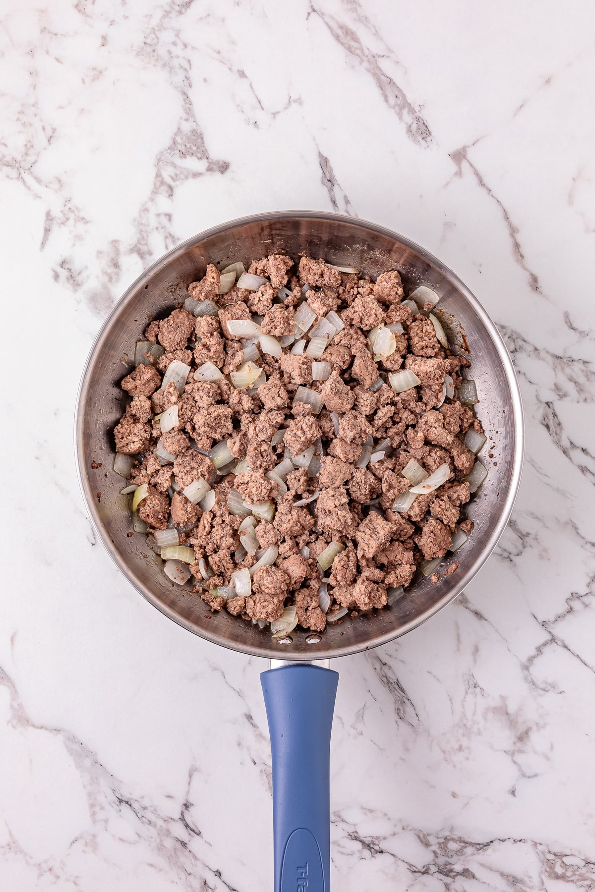 Ground beef and onion cooked in skillet.