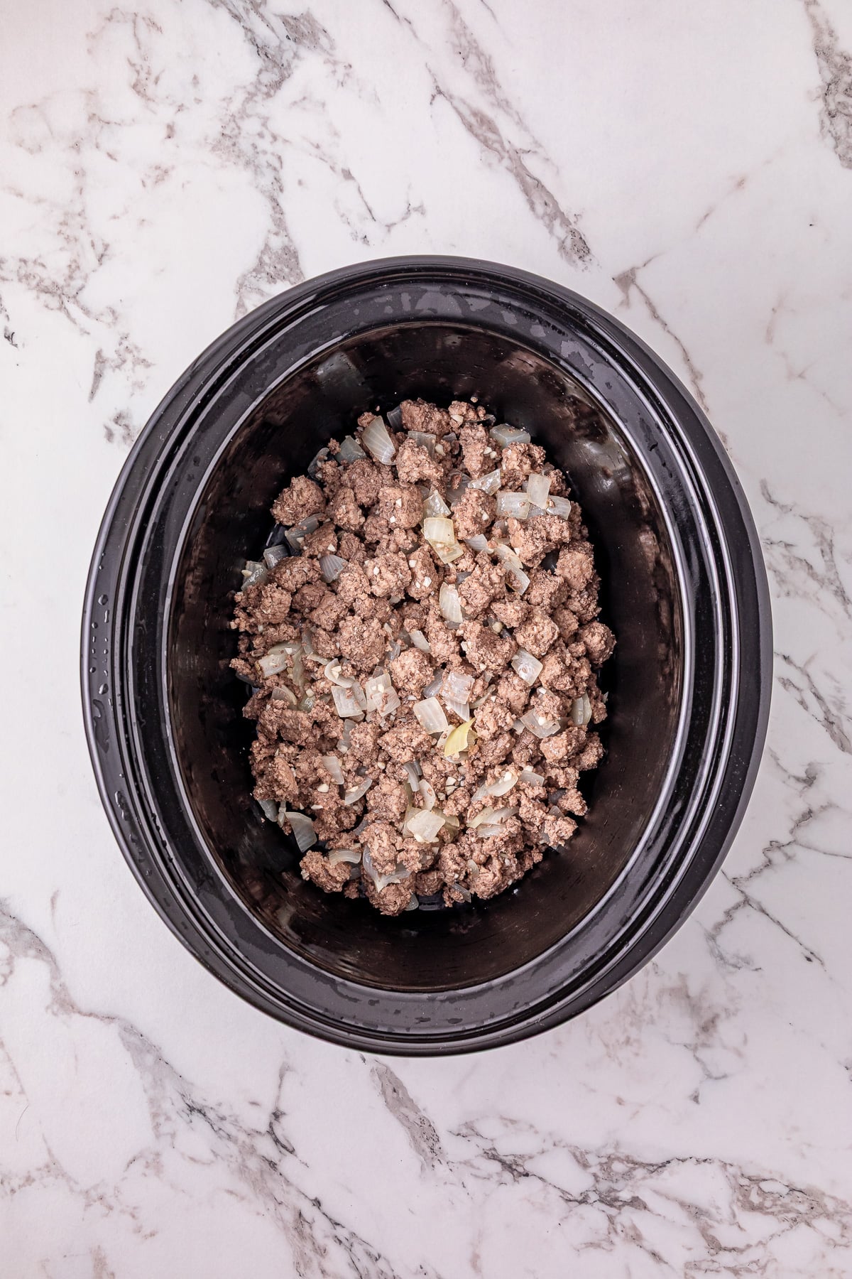 Cooked ground beef mixture in bottom of slow cooker.