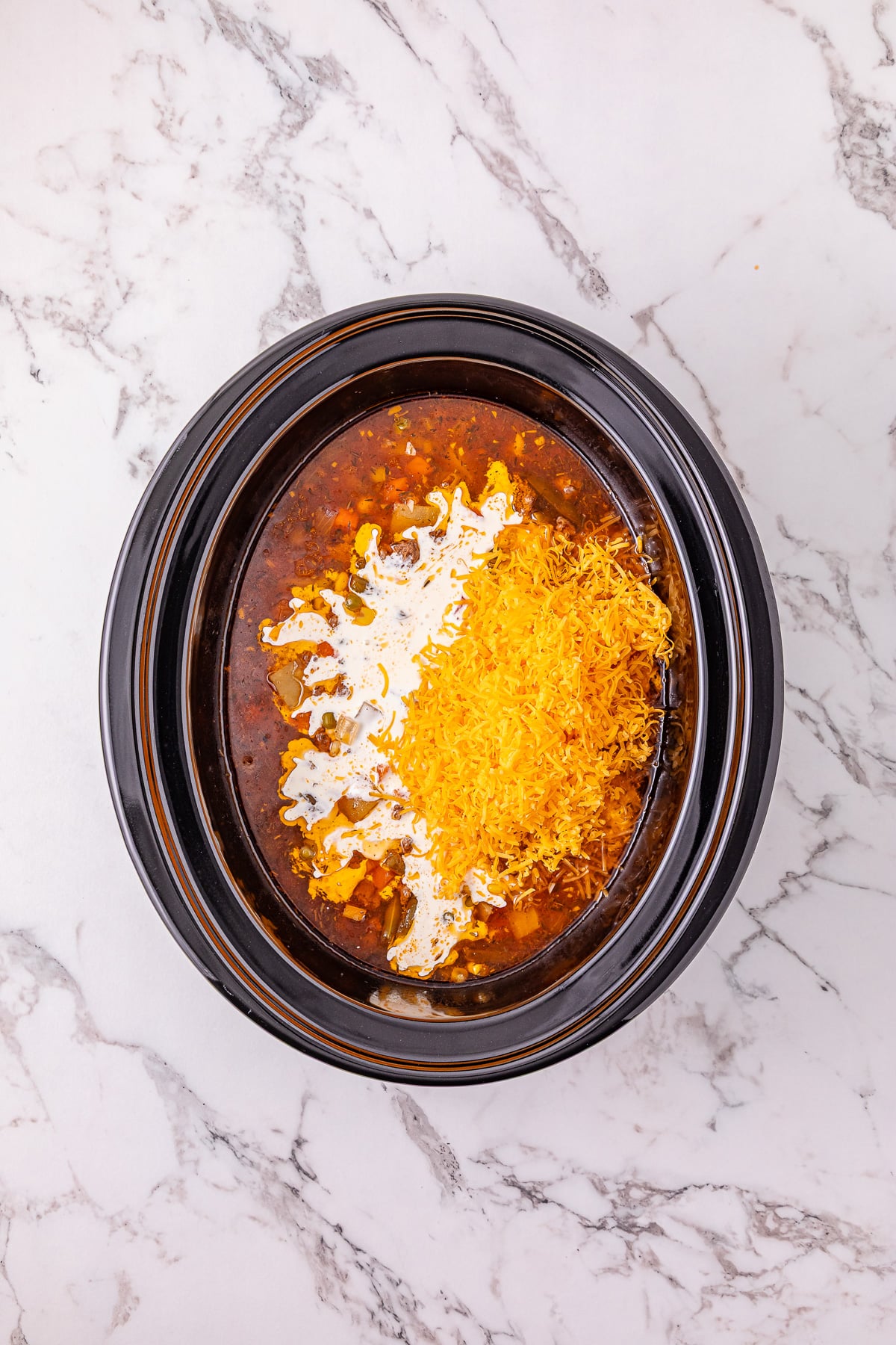 Heavy cream and shredded cheese are added to the slow cooker.
