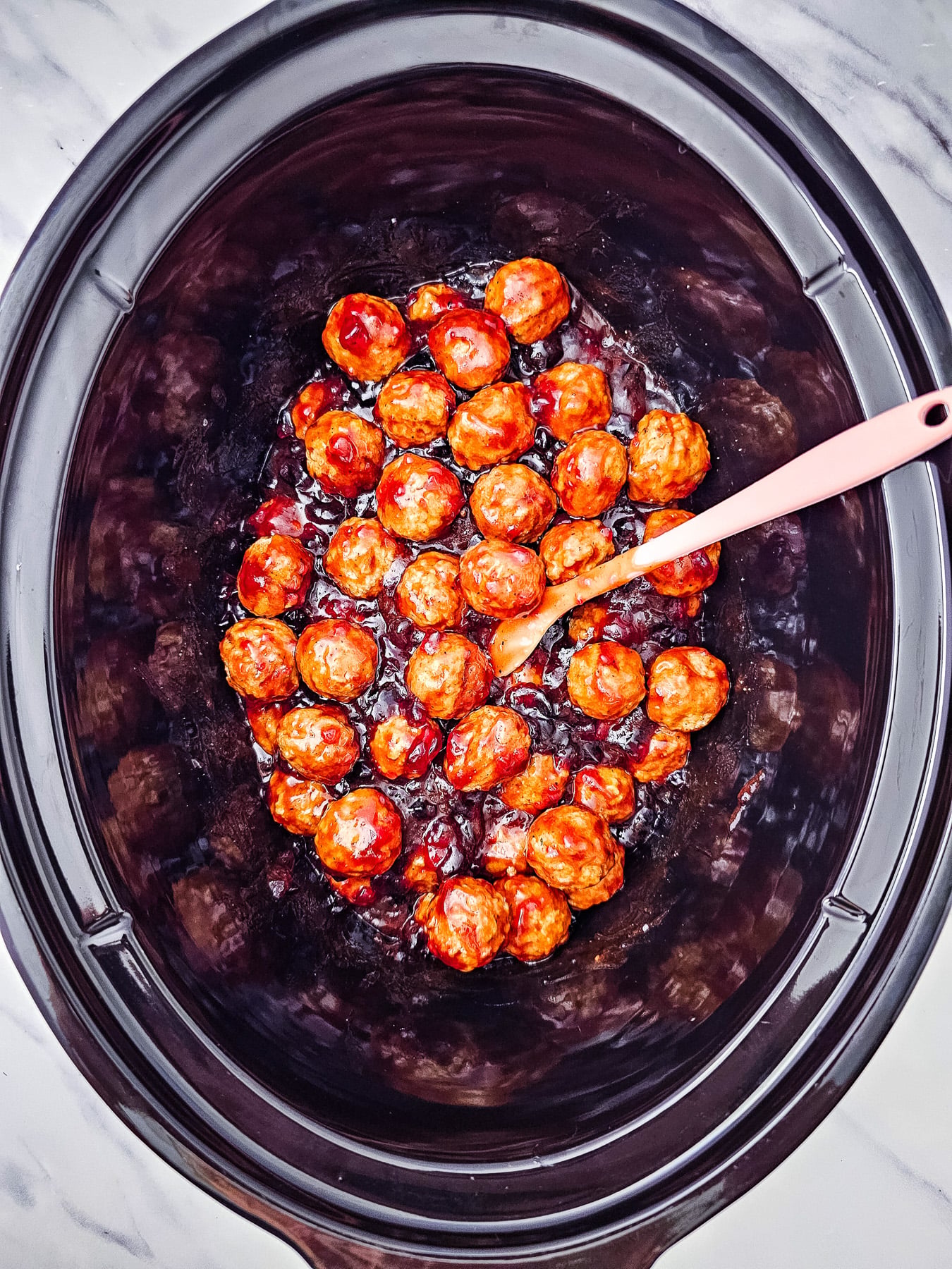 Frozen meatballs are added to the slow cooker and stirred into the bbq sauce and grape jelly.
