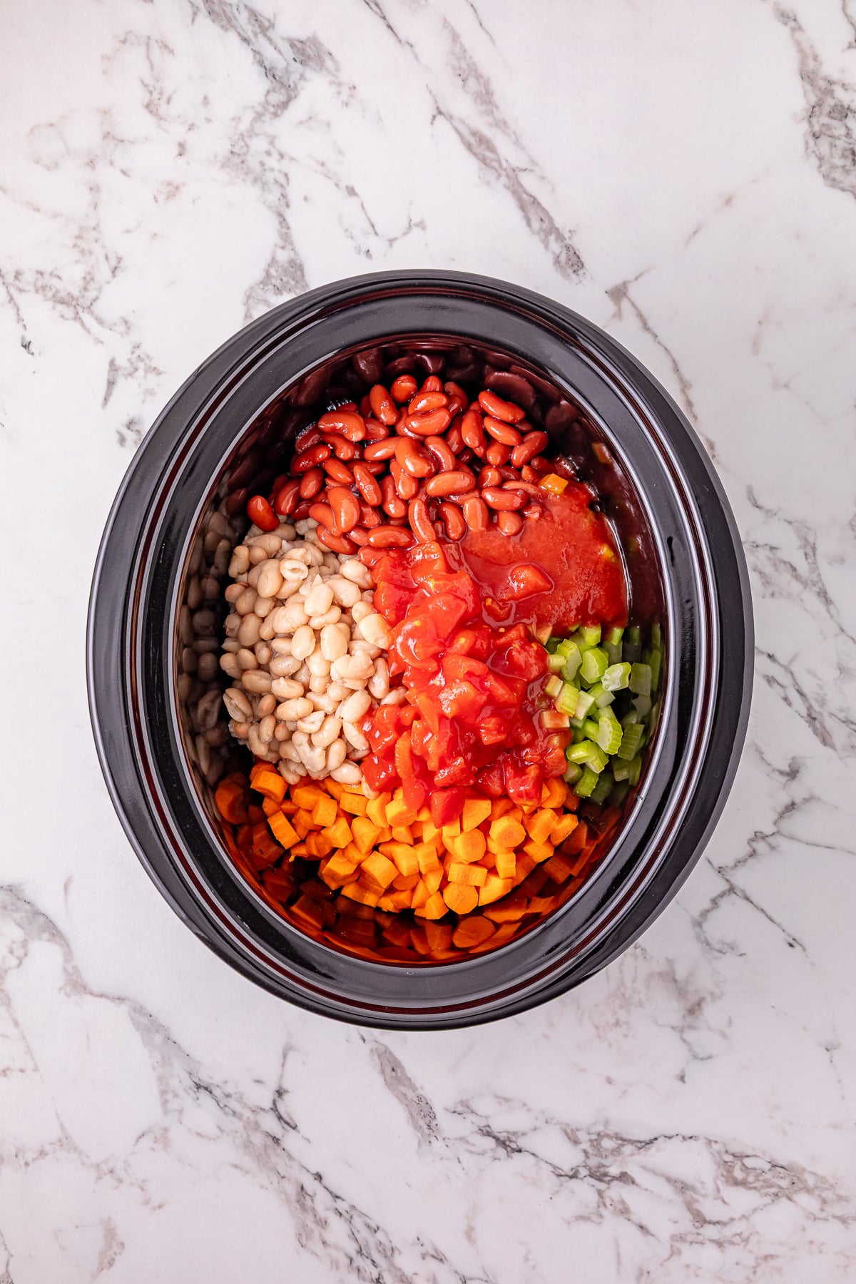 Carrots, celery, kidney beans, great northern beans, diced tomatoes with their juices, and tomato sauce in crockpot.