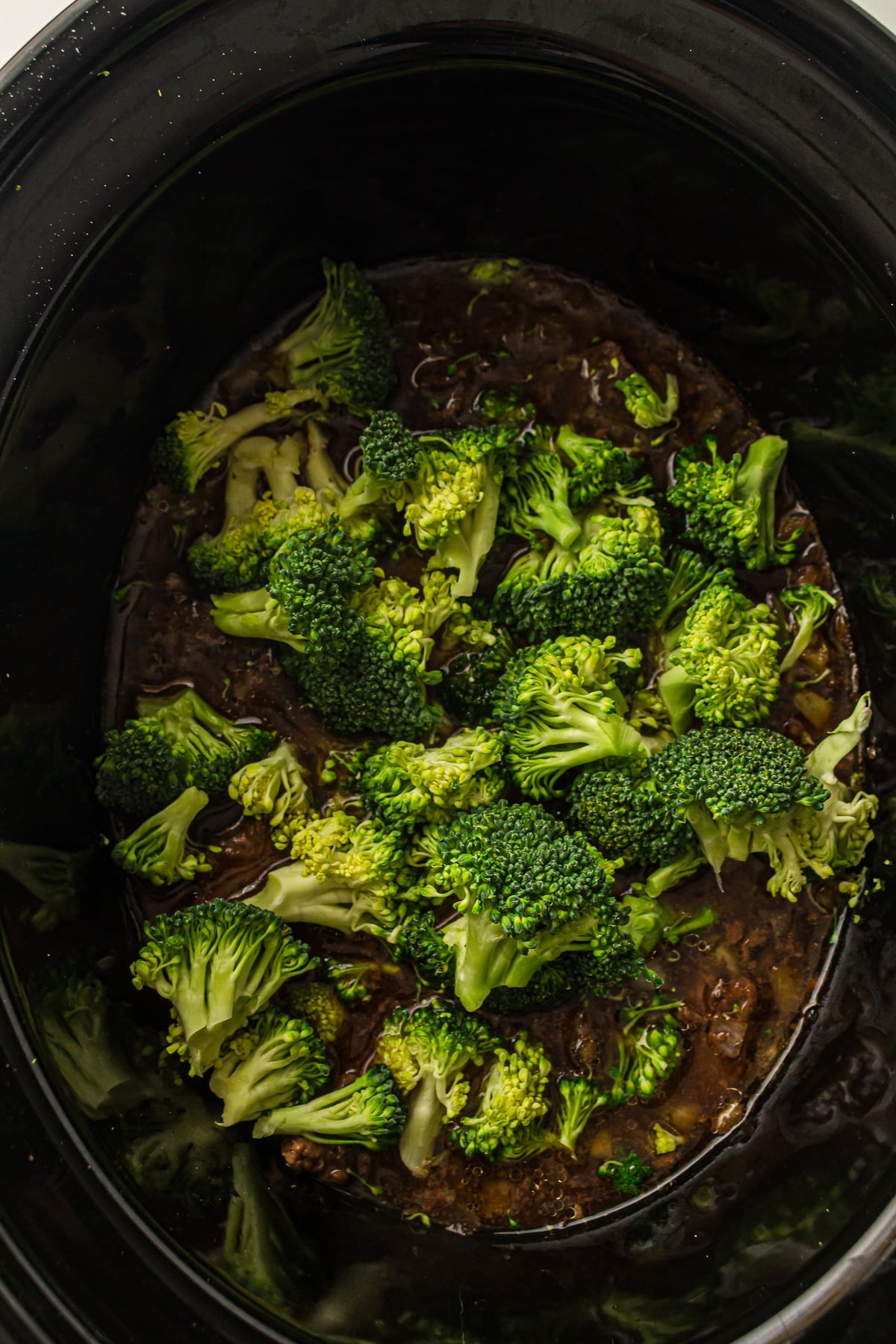Broccoli is added to the slow cooker.